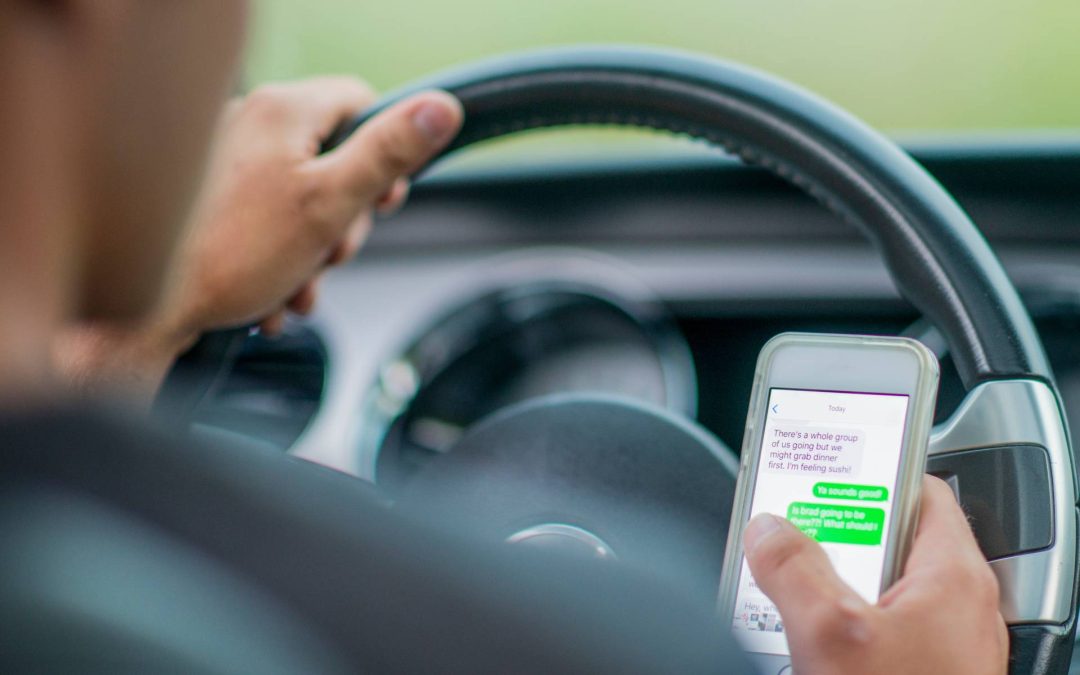 male driver looking at text messages while driving